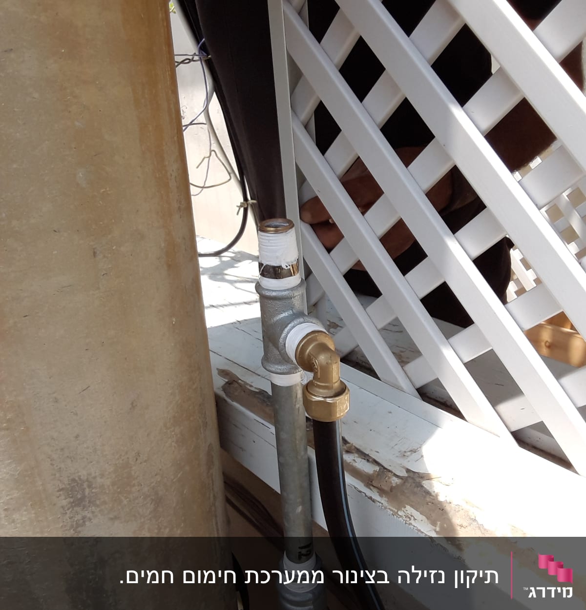 צינור מתכת עם חיבורי פליז ליד מחיצה לבנה